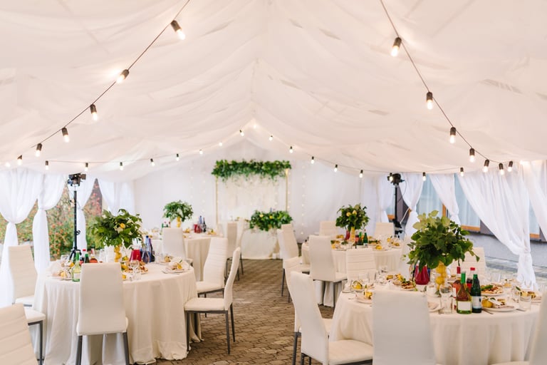 Bodegón nupcial con arco decorado con luces y mesas de banquet