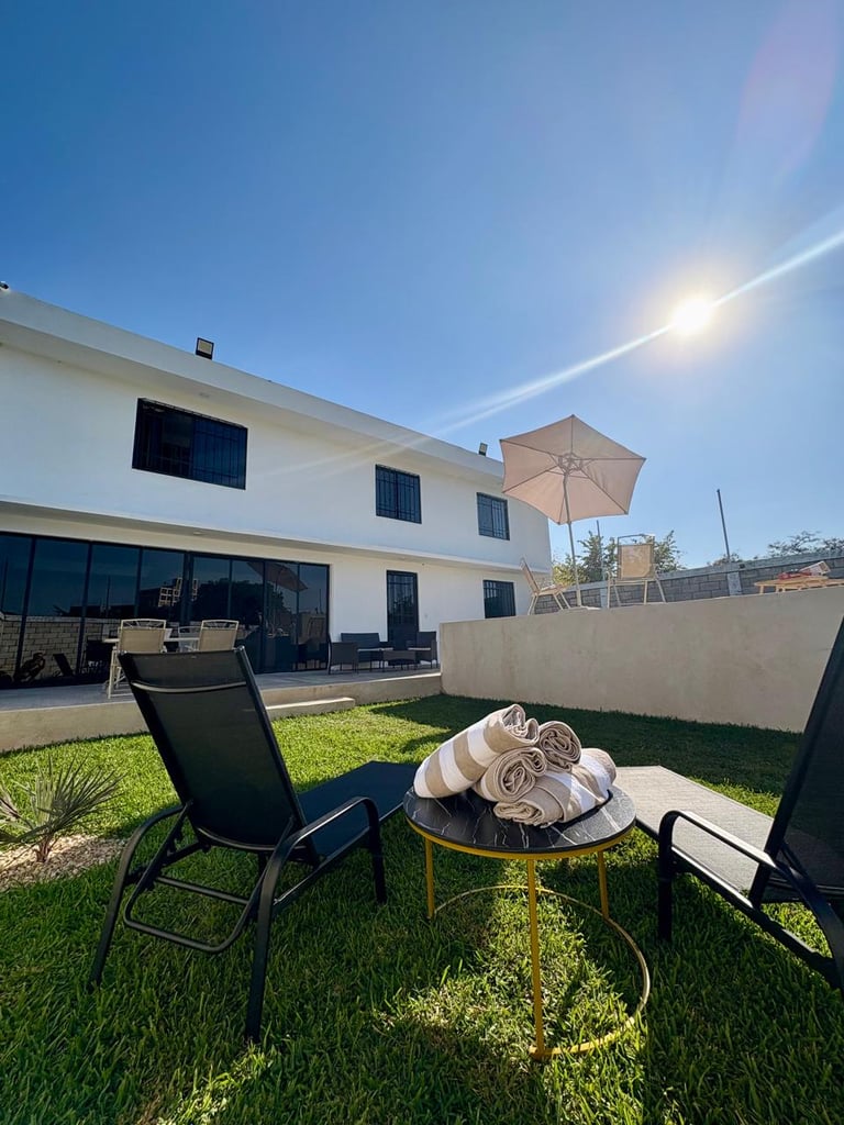 Modern white house with backyard patio featuring lounge chairs